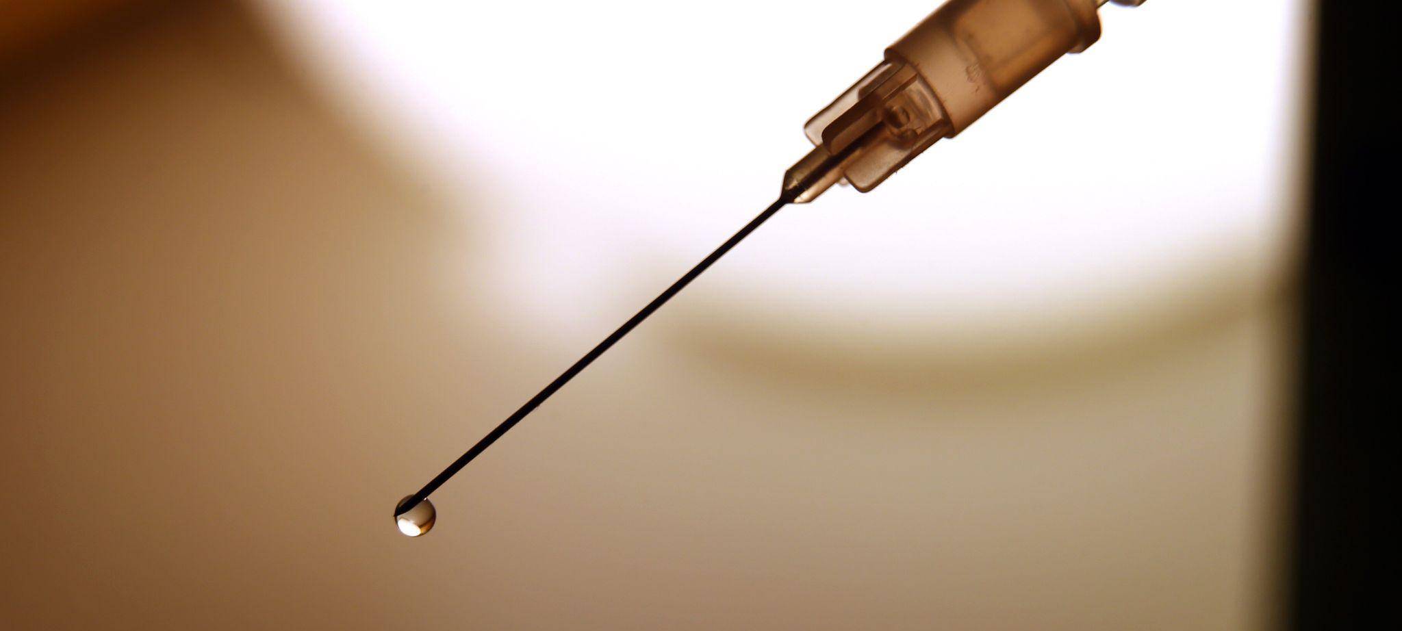 Eine Flüssigkeit tropft aus der Kanüle einer Spritze