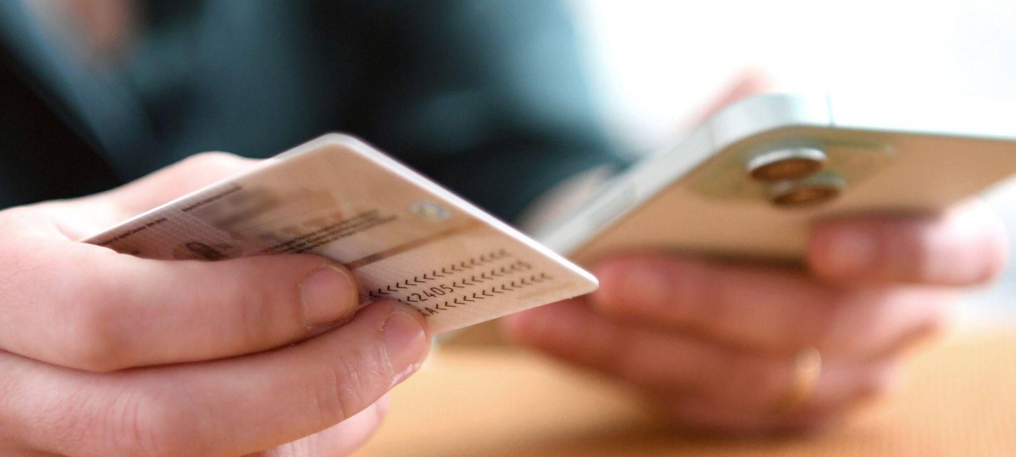 Eine Frau hält Personalausweis und Smartphone in den Händen