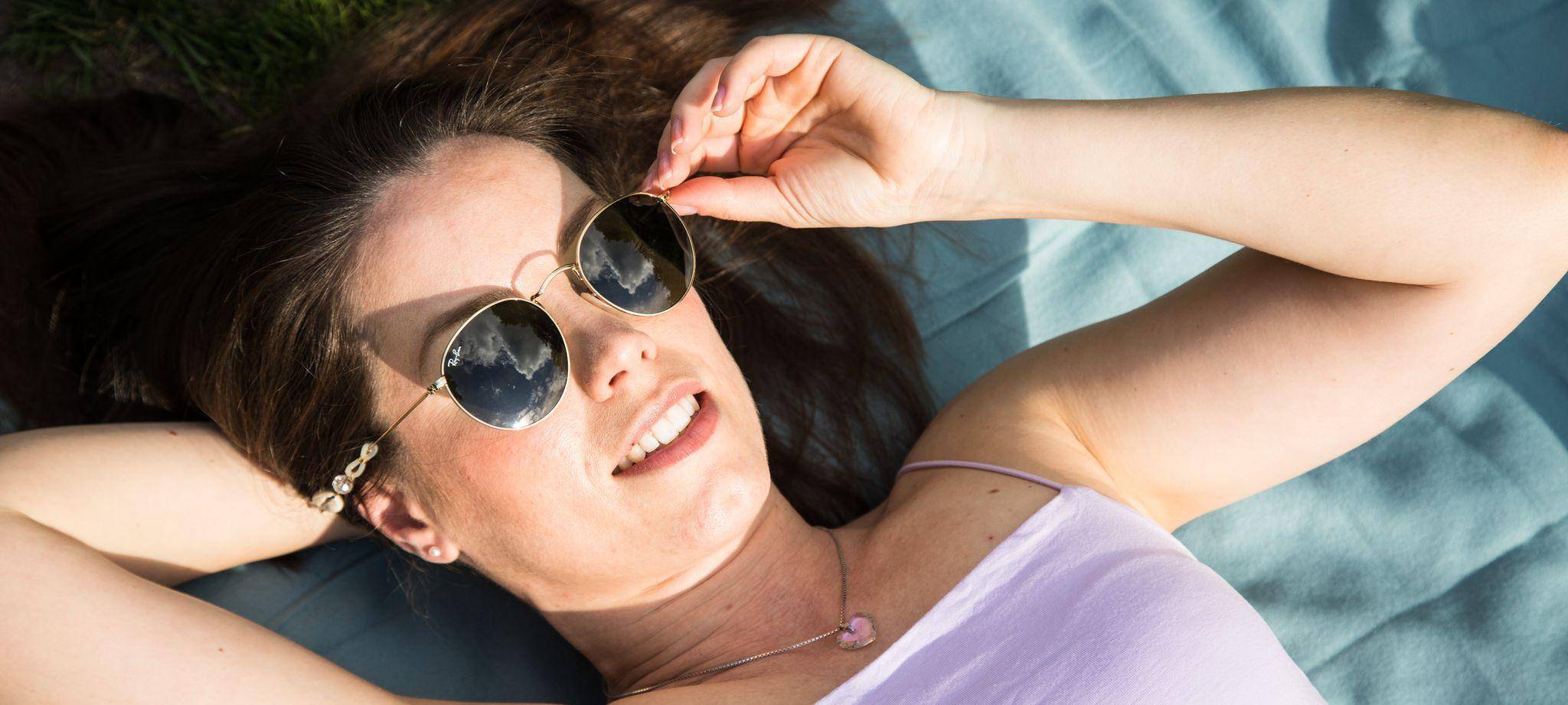 Frau mit Sonnenbrille sonnt sich im Park