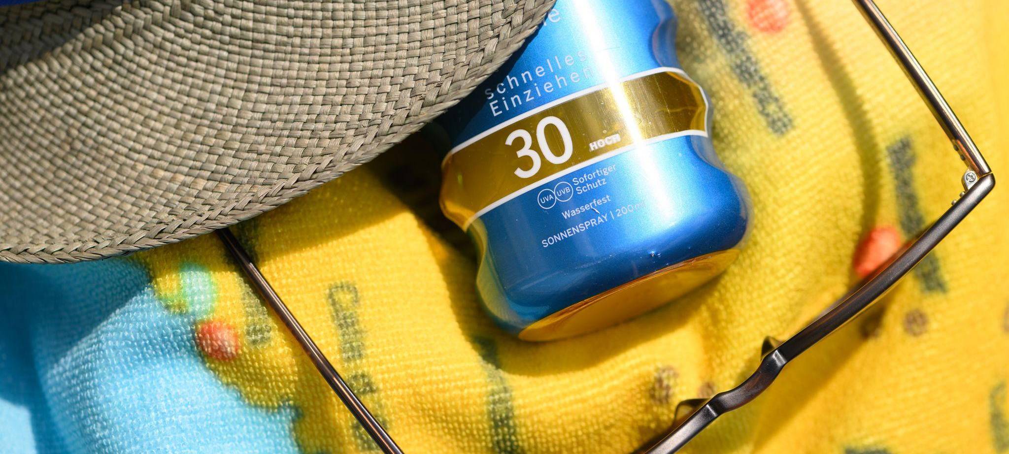 Sonnenspray, eine Sonnenbrille und ein Sommerhut